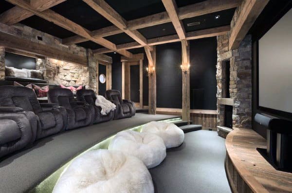 Home theater with cozy recliners, plush seating, stone walls, wooden beams, and ambient lighting