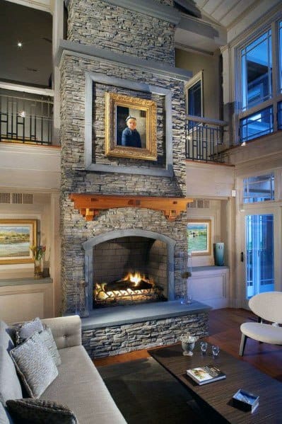 Cozy living room with stacked stone fireplace, modern decor, and a portrait above