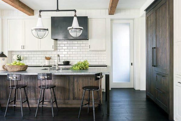 Modern rustic kitchen with white cabinets, a dark wood island, subway tile backsplash, and industrial pendant lighting.