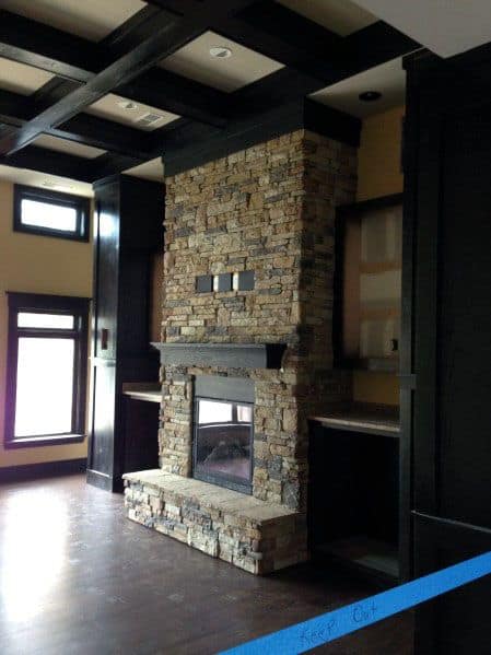 Living room with stacked stone fireplace, dark wood beams, and hardwood flooring