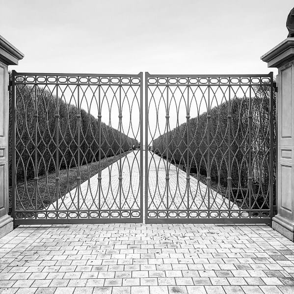 Intricate iron driveway gate with wavy lattice design and circular accents.