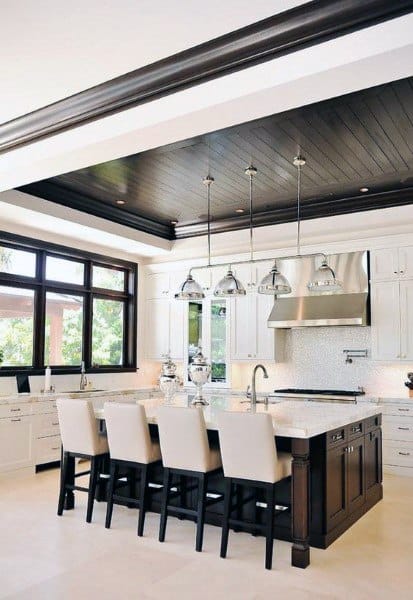 Luxurious kitchen with dark wood ceiling island seating stainless steel hood and pendant lights.