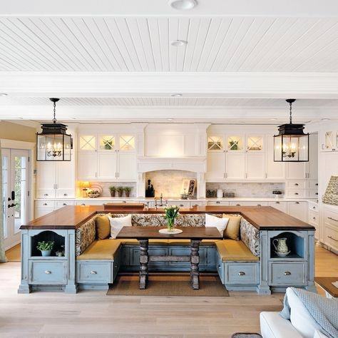 Bright kitchen with white cabinets, a wooden island with seating, and a cozy nook adorned by decorative lanterns