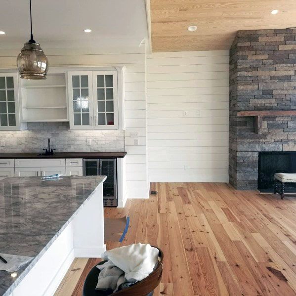 Modern kitchen with stacked stone fireplace, marble countertop, and wood flooring