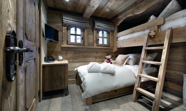 Cozy rustic room with bunk beds, a small TV, and a teddy bear adding charm to the bed