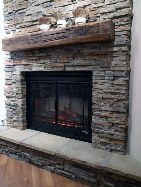 Stacked stone fireplace with a wooden mantel and decorative items on top