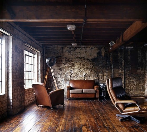 Loft space with leather furniture, large windows, exposed brick walls, and wooden flooring