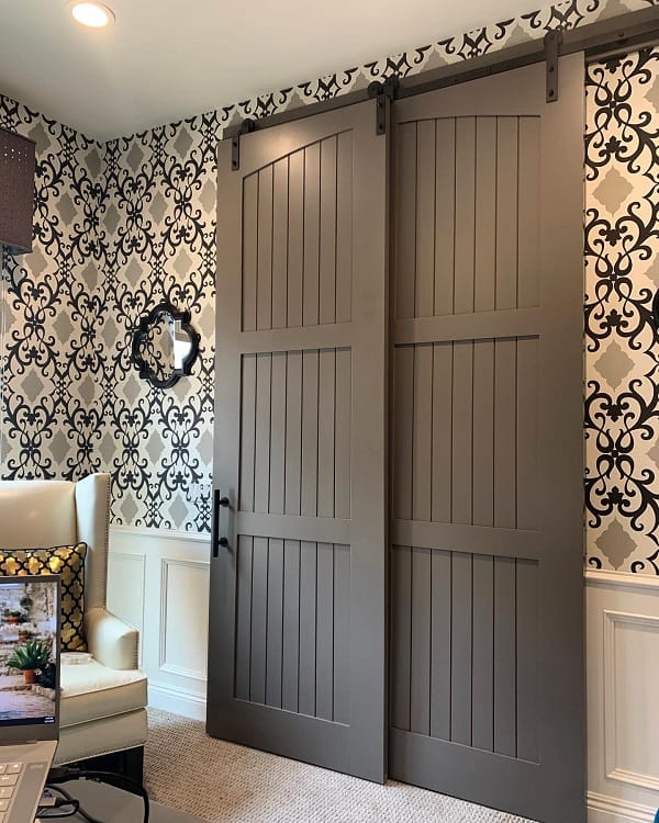 Rustic modern double sliding barn doors in a home office with patterned wallpaper and cozy seating.