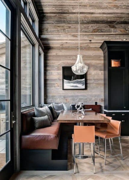 Cozy nook with leather bench, sleek table, and modern chairs, set against wood-paneled walls and large windows