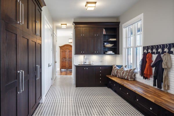 rustic cabinet mudroom with black and white floor tiles and bench seating