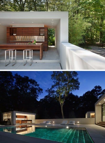Modern outdoor kitchen and pool area surrounded by trees, featuring sleek design and ambient lighting