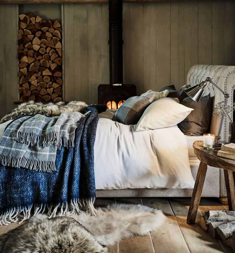 rustic cabin style bedroom with fireplace and log storage 