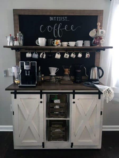 White coffee bar with sliding barn doors, chalkboard sign, hanging mugs, and brewing equipment.
