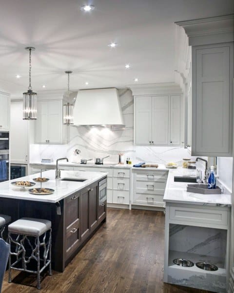 Elegant kitchen with white marble backsplash, dark island, and hardwood flooring.