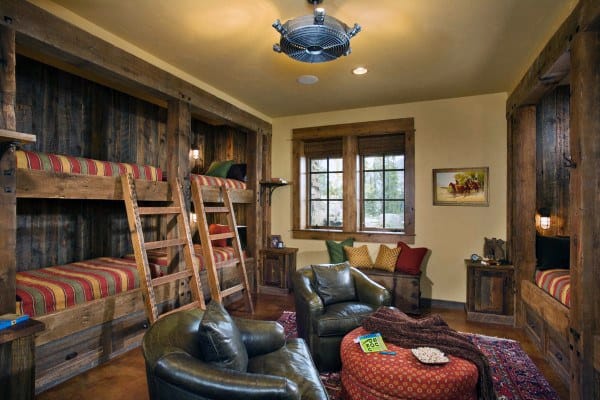 Rustic wooden bunk beds with red striped bedding, cozy lounge chairs, and warm lighting, perfect for a cabin-style room