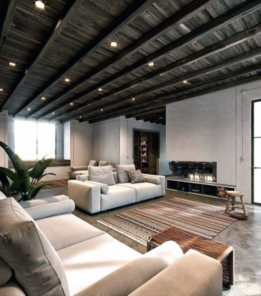 Rustic living room with exposed wood beams, neutral sofas, and a modern fireplace.