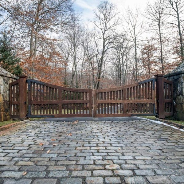 Rustic wooden driveway gate with arched top and vertical slat design.