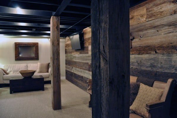 Basement with rustic wood poles, reclaimed wood walls, and cozy seating area.