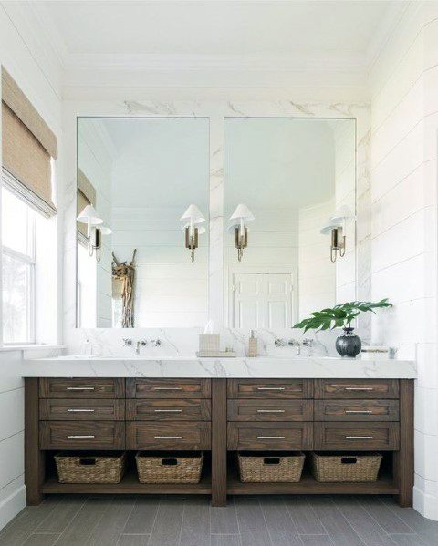 Rustic wood vanity with marble countertop, large mirrors, and wicker basket storage.