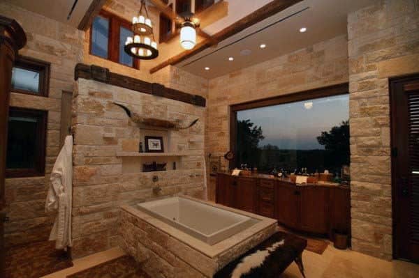 Rustic bathroom featuring stone walls, a large window, and a central bathtub