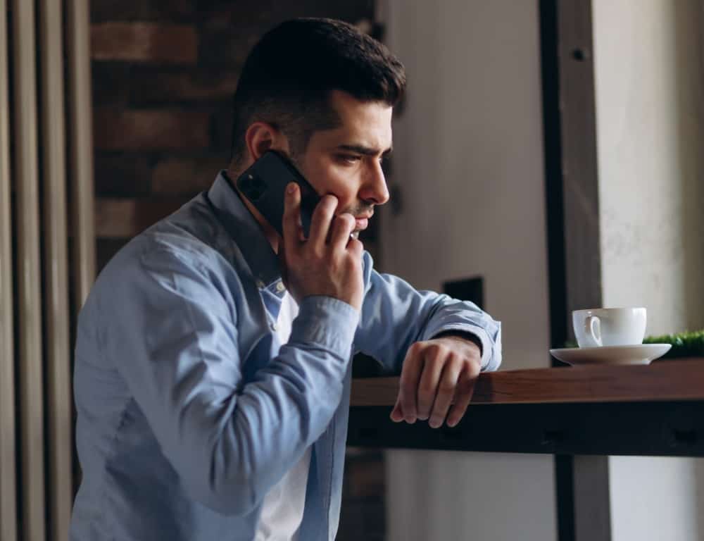 sad man talking on the phone in a coffee shop