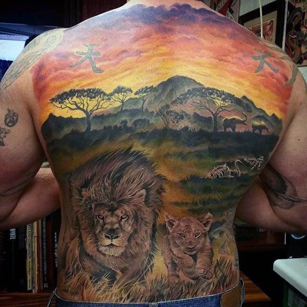 Back tattoo of a lion and cub in an African savannah scene with trees and sunset