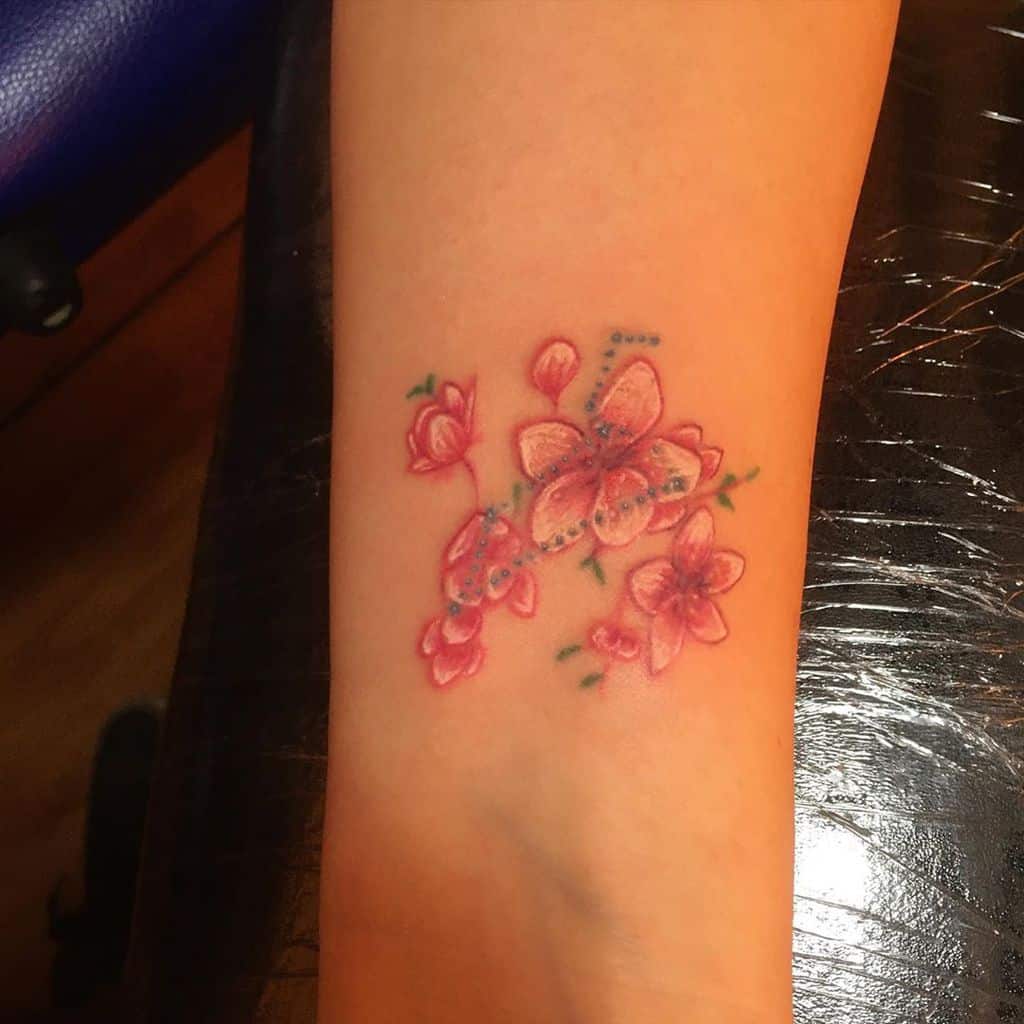 Tiny butterfly tattoo with blooming pink flowers, symbolizing transformation, beauty, and nature’s grace.