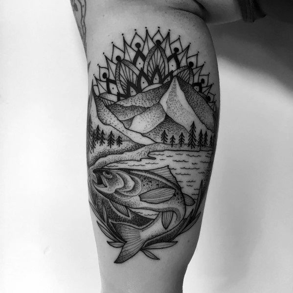 Black and grey dotwork tattoo of a salmon leaping from a river, framed by mountains, trees, and a mandala, creating a nature-inspired leg design.