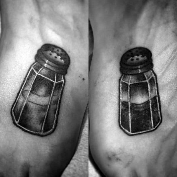 Matching tattoos of a salt and pepper shaker on feet, symbolizing a perfectly seasoned and complementary relationship full of flavor and fun.