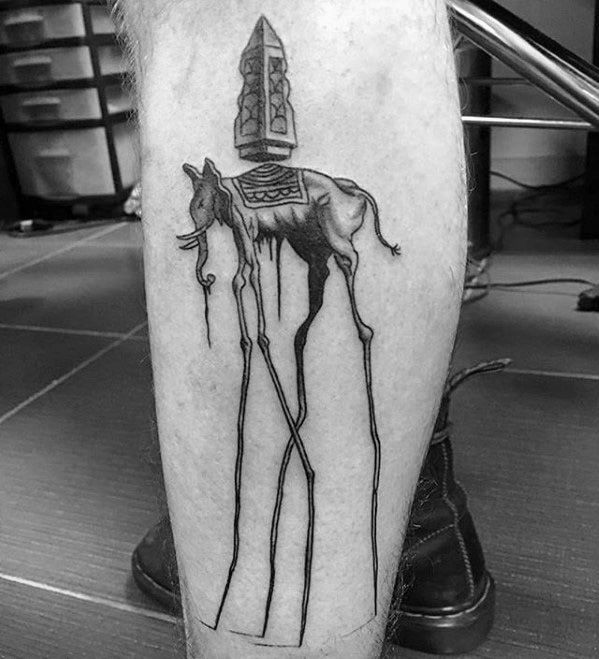 Black and grey calf tattoo of a Salvador Dali-style elephant with long, thin legs and a detailed obelisk on its back, dripping with surrealism.