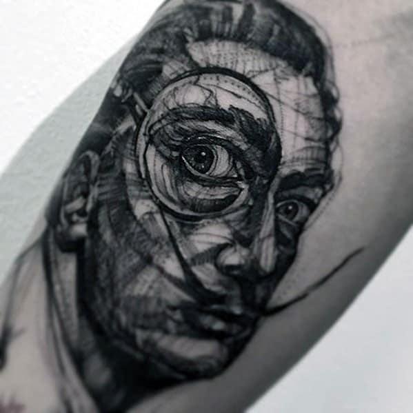 Abstract blackwork tattoo of Salvador Dali with a sketch-style finish, intense gaze, monocle detail, and surreal linework across the face.
