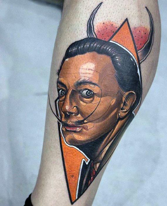 Bold geometric tattoo of Salvador Dali with sharp orange accents, detailed facial shading, and subtle surreal horns blending into the design.
