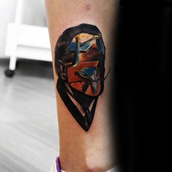 Surreal tattoo of Salvador Dali with his face blending into a dreamlike scene of melting clocks, desert landscapes, and abstract forms.