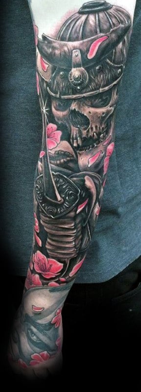 Samurai-themed full sleeve tattoo featuring a detailed skull in a helmet, a sword, and pink cherry blossoms for a bold warrior aesthetic