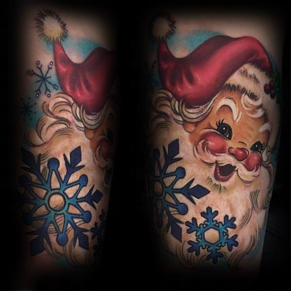 Vintage-style Santa Claus tattoo with bright colors, rosy cheeks, and a cheerful expression, surrounded by bold blue snowflakes for a festive touch.