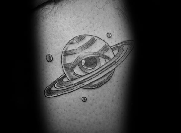 Surreal Saturn tattoo design for men featuring an eye within the planet, surrounded by orbiting moons in black and grey shading.