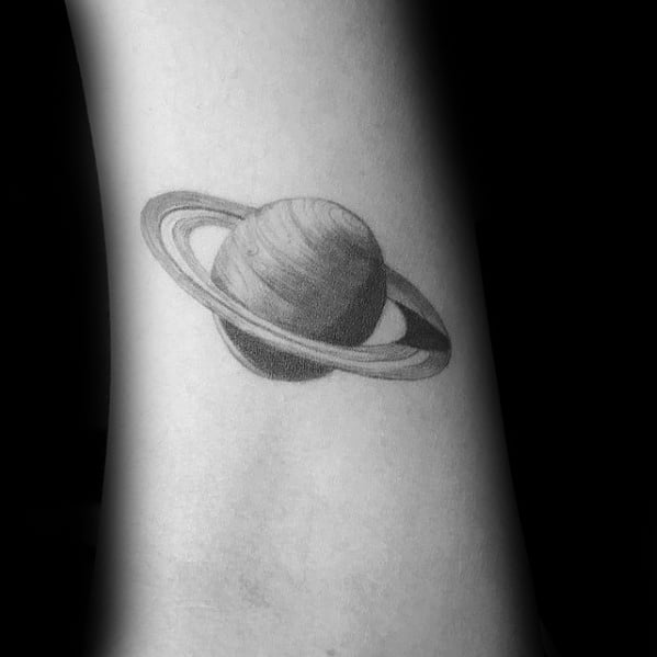 Realistic Saturn tattoo design for men with soft black and grey shading, fine ring details, and a clean minimal layout on the forearm.