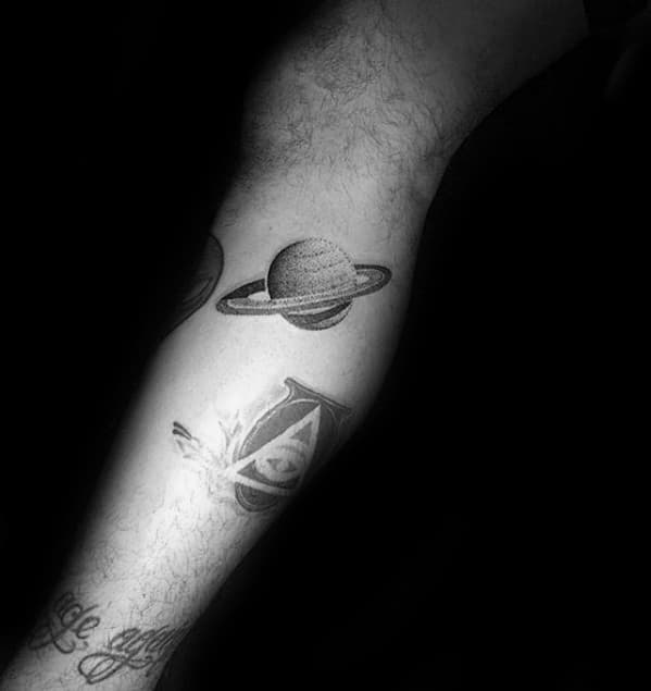 Minimal Saturn tattoo design for men on the calf with fine dotwork shading and clean ring lines in a simple black ink style.