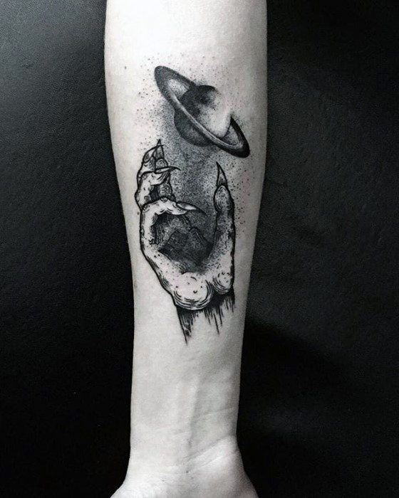 Blackwork Saturn tattoo design for men featuring a skeletal hand gently holding the ringed planet, with soft dot shading and surreal detail.