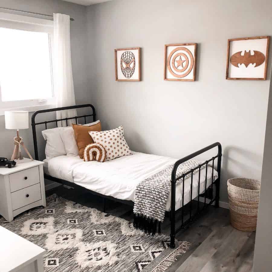 Kids' bedroom with black metal bed, superhero wall art, and cozy neutral decor.