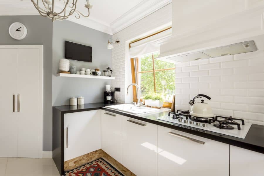 Bright kitchen with white cabinets, black countertops, and white brick backsplash.