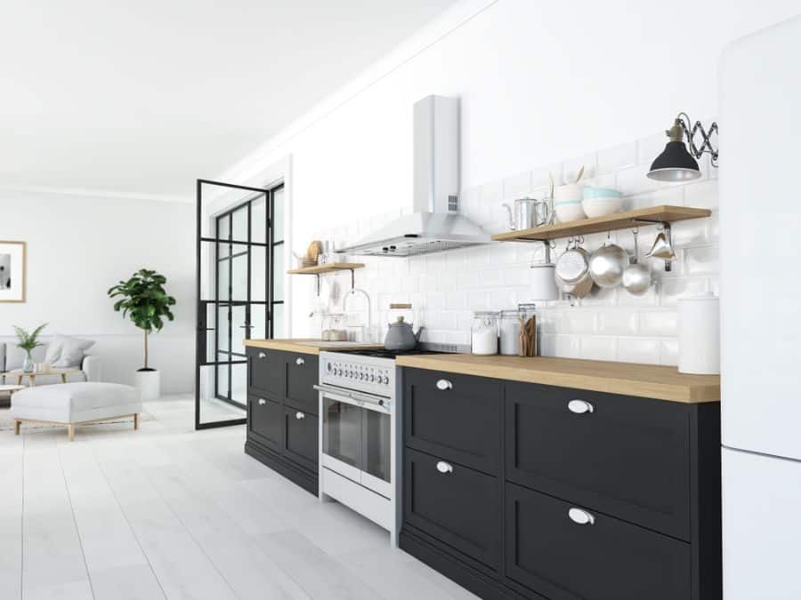 Scandinavian kitchen with black cabinets, wooden countertops, and white subway tile backsplash.