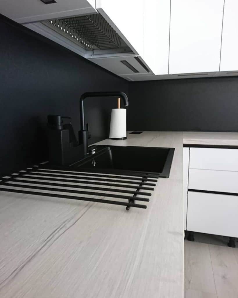 Modern black sink with white countertop and black faucet in a sleek kitchen.