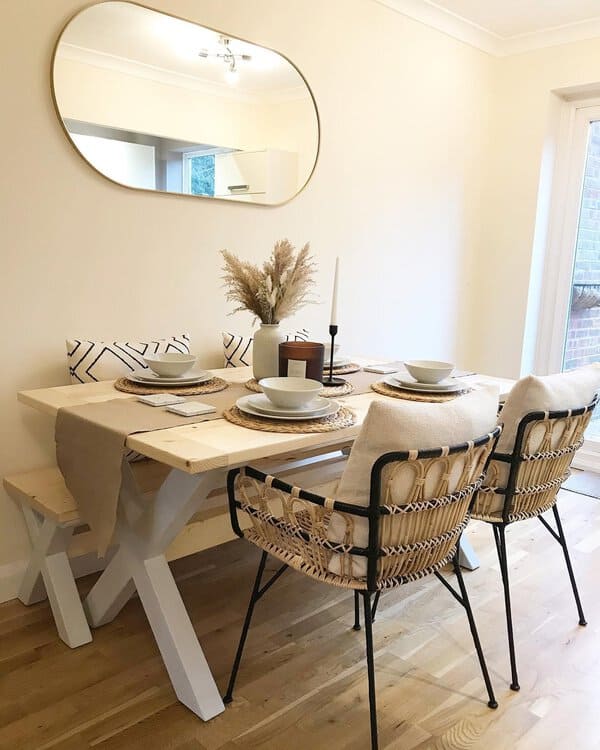 Scandinavian boho dining room with minimalist wooden table, woven chairs, and pampas centerpiece.