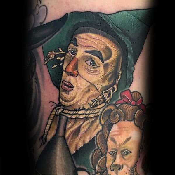 Colorful tattoo of the Scarecrow from *The Wizard of Oz*, featuring realistic facial details, green hat, rope neck, and bold outlines.