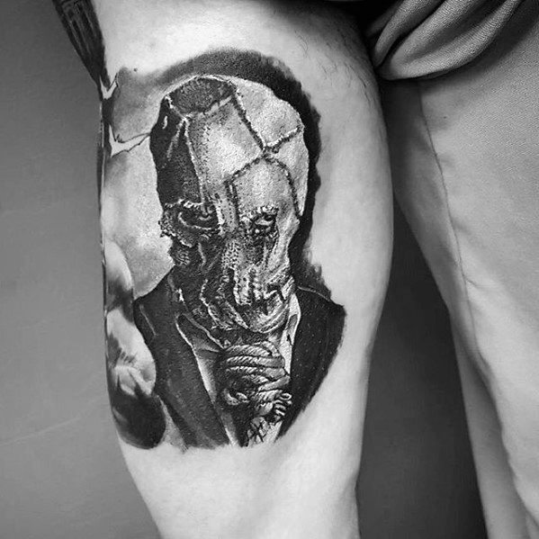 Realistic scarecrow tattoo on the thigh featuring a cracked burlap mask, rope around the neck, and intense black and grey shading.