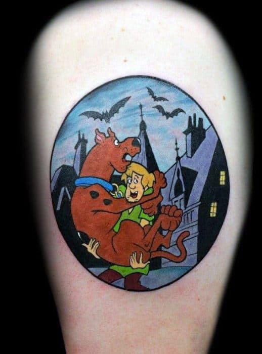 Scooby-Doo and Shaggy tattoo in a spooky night scene, with bats flying over haunted houses and Scooby jumping into Shaggy’s arms.