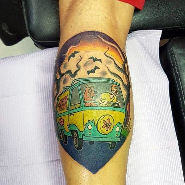 Tattoo of the Mystery Machine with Scooby-Doo and the gang driving through a spooky forest under an eerie sky with bats flying.