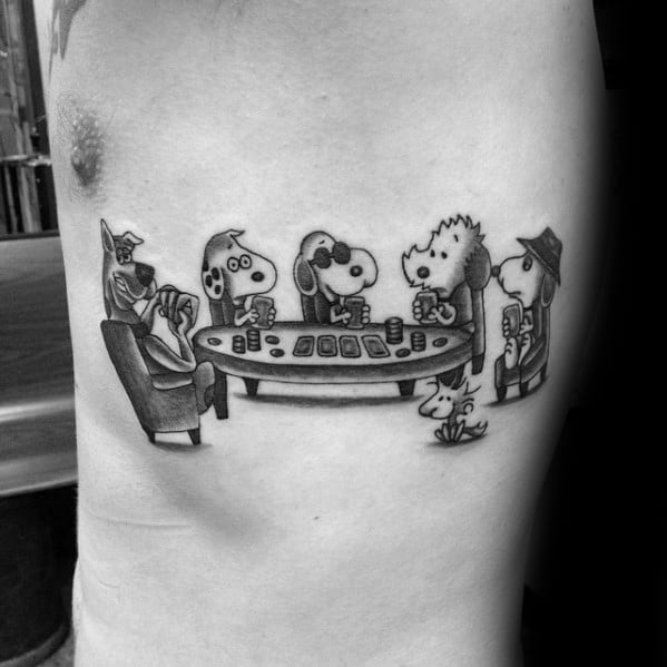 Black and white tattoo of Snoopy characters and Scooby-Doo dressed up and playing poker around a table, with Woodstock sitting nearby.