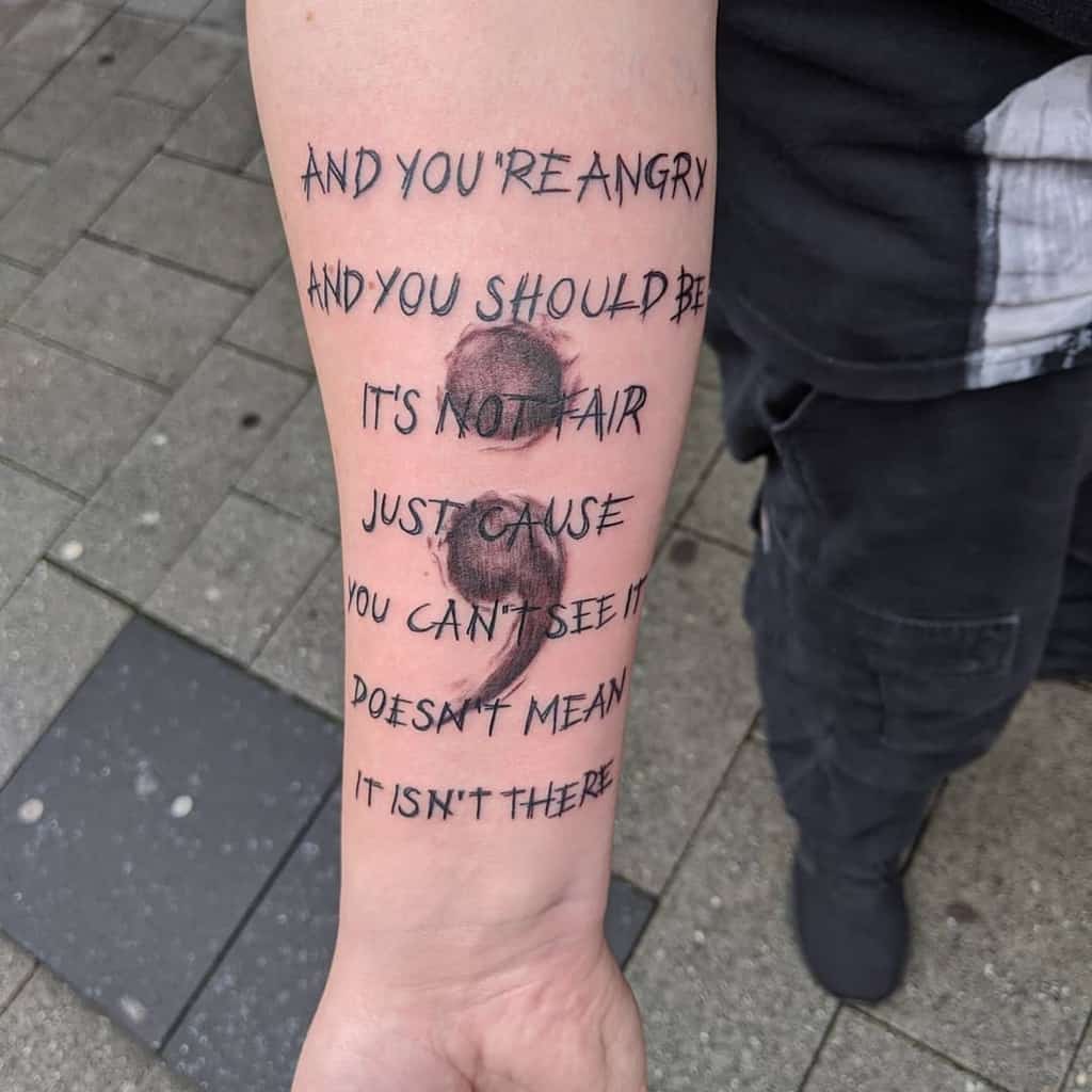 This tattoo features lyrics from a song, expressing emotions of frustration and resilience. The tattoo is accompanied by a symbolic semicolon, signifying strength and perseverance in the face of adversity.